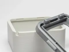 Close-up of a 3D-printed white box and a grey lid, showcasing the intricate snap fit joints designed for easy assembly.