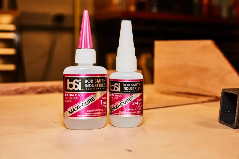 Two bottles of Bob Smith Industries Maxi-Cure glue, explaining why super glue is so strong due to its cyanoacrylate formula.