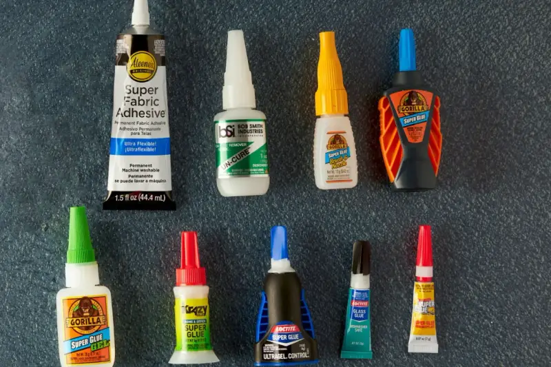A collection of super glue bottles, including Gorilla Glue and Krazy Glue, are laid out for a comparison of bondic vs super glue.