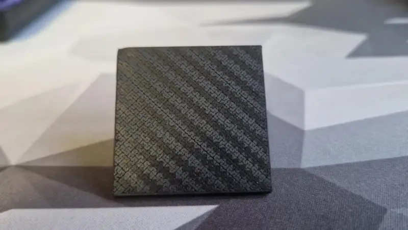 A small cube with a textured surface, showcasing the intricate pattern achieved through carbon fiber 3D printing.